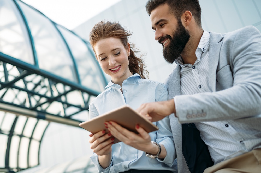 Junior Account Manager Man en vrouw kijken naar een tablet buiten